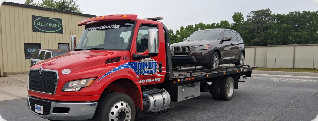 Red tow truck with car loaded